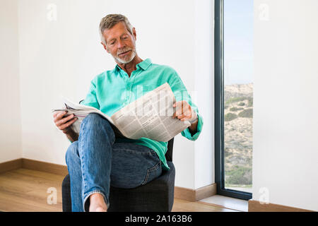 Senior man reading newspaper at home Stock Photo