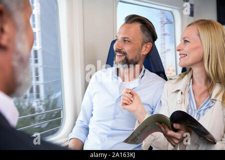 Couple traveling by train, reading magazine Stock Photo