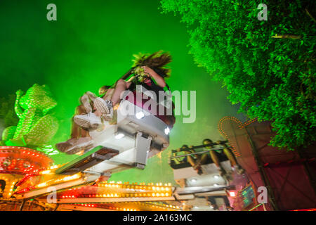 People in a fairground ride on a funfair at night Stock Photo