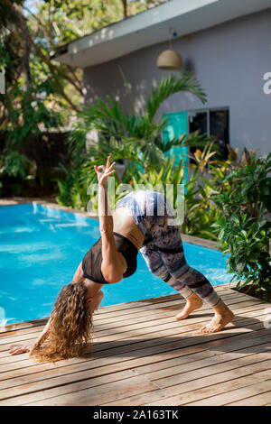 Woman practicing yoga at poolside, Costa Rica Stock Photo