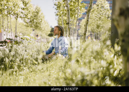 Young man meditating in urban park Stock Photo