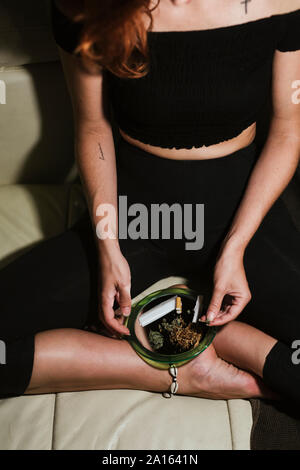 Young woman rolling a joint at home Stock Photo