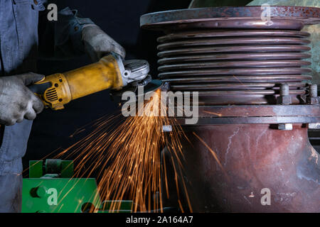 Close-up of worker using angle grinder in a factory Stock Photo