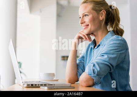 Blond woman sitting in coffee shop, using laptop Stock Photo