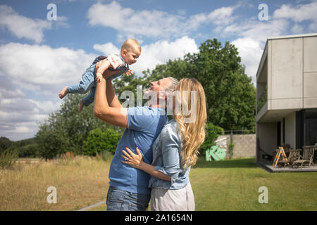 Happy father with mother lifting up baby girl in garden Stock Photo