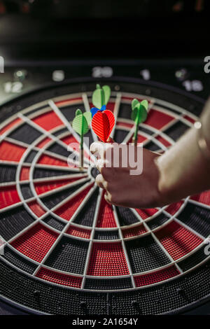 Close-up of woman's hand with darts in electronic dartboard Stock Photo