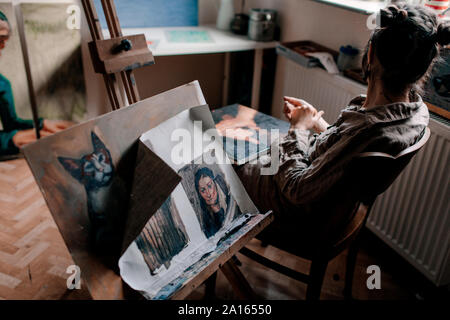 Female artist sitting in her studio with paintings Stock Photo
