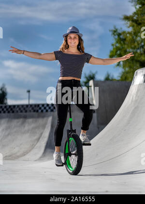 Young woman riding unicycle in skatepark Stock Photo