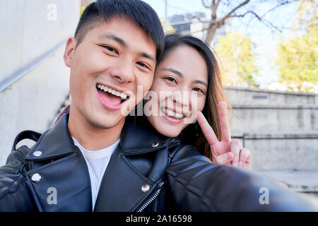 Portrait of happy young couple making victory sign Stock Photo