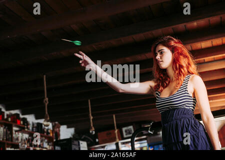 Young woman playing darts in a sports bar Stock Photo