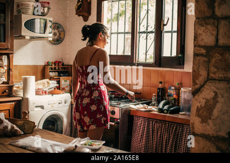 Rear view of woman cooking in kitchen Stock Photo