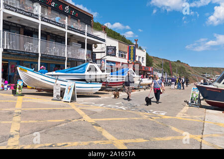 dh Coble landing FILEY NORTH YORKSHIRE People couple walking dogs boats Stock Photo