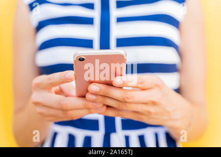 Young woman using smartphone, focus on the foreground Stock Photo