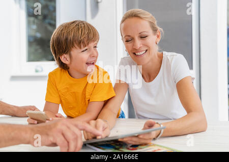 Happy mother and son doing homework  and using tablet together on terrace Stock Photo