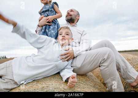Father and his children playing and laughing on hay bales Stock Photo
