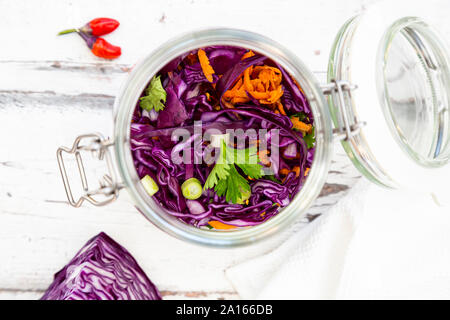 Jar of red cabbage, chili peppers, carrots and coriander on wooden table Stock Photo