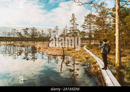 Woman with backpack standing on boardwalk in autumn looking at view, Lahemaa National Park, Estonia Stock Photo