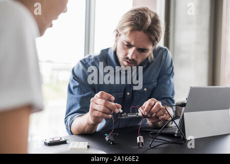 Young man and woman working on computer equipment in office Stock Photo