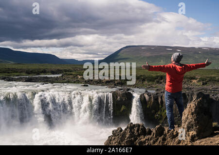 Man looking at Godafoss waterfalls, Iceland, with arms outstretched Stock Photo