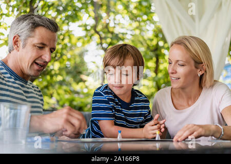 Happy parents and son playing a board game on terrace Stock Photo