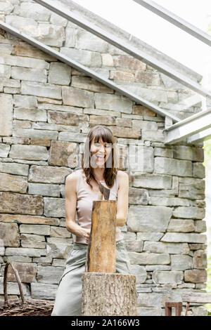 Screaming woman chopping wood in front of a house Stock Photo