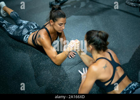 Twin sisters doing arm wrestling in gym