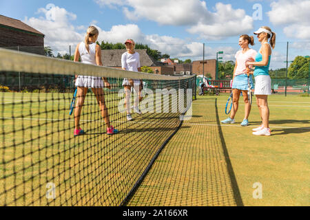 Mature women talking on grass court at tennis club Stock Photo