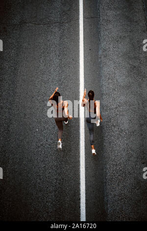 Top view of two sporty twin sisters running on a street Stock Photo