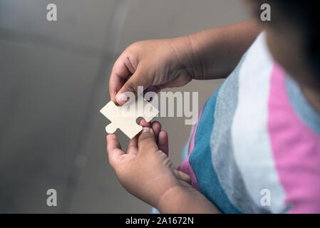 A toddler holding a jigsaw puzzle block Stock Photo