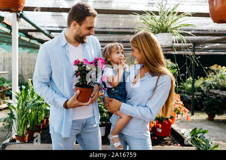 Happy mother, father and daughter buying flowers in a garden center Stock Photo