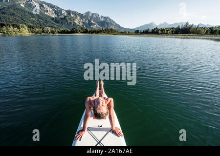 Smiling girl on a stand up paddle board, Bannwaldsee, Allgaeu, Bavaria, Germany Stock Photo