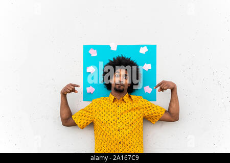 Young man wearing yellow shirt, blue indicating label with arrow signs Stock Photo
