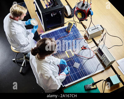 Two technicians working on 3d printed turbine wheel and solar panel in lab Stock Photo