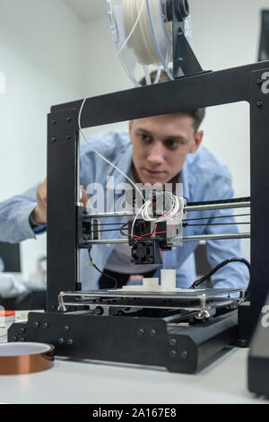 Student setting up 3D printer, using laptop Stock Photo