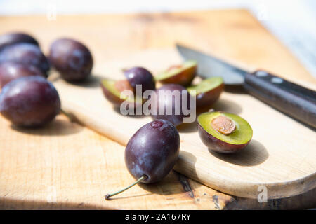 Purple plums on wooden cutting board Stock Photo