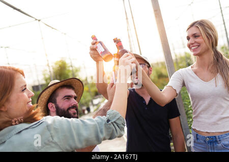 Group of friends toasting with bottles of beer in the greenhouse Stock Photo