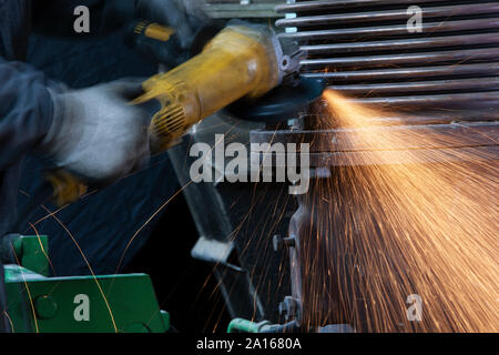 Close-up of worker using angle grinder in a factory Stock Photo