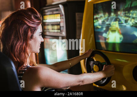 Young woman using driving simulator in a sports bar Stock Photo