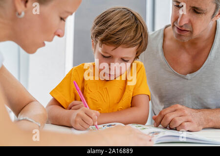 Father, mother and son doing homework together on terrace Stock Photo