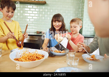 Mother eating spaghetti with her sons in the kitchen Stock Photo