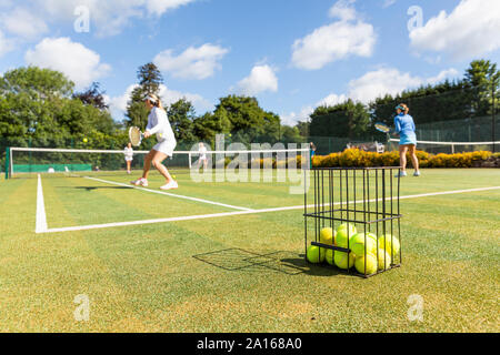 Mature women playing tennis on grass court Stock Photo