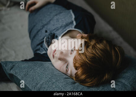 Portrait of daydreaming boy lying on couch looking at distance Stock Photo