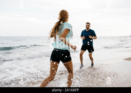 Young couple jogging on the beach Stock Photo