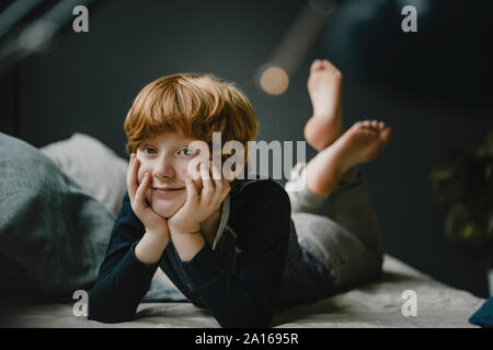 Portrait of smiling redheaded boy lying on couch at home Stock Photo