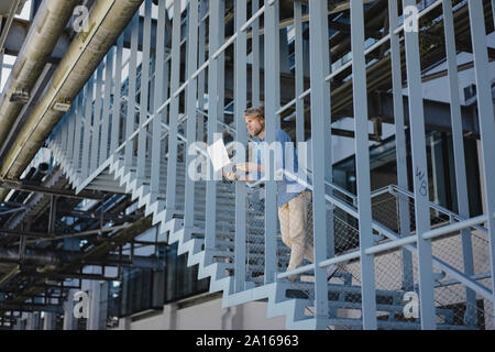 Young man standing on stairs using laptop Stock Photo