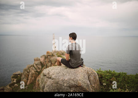 Trail runner sitting on a rock in coastal landscape, Ferrol, Spain Stock Photo