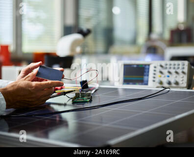 Technician holding silicon solar cell on solar panel Stock Photo