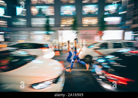 Long exposure photo of two women running through the streets in the city at night Stock Photo