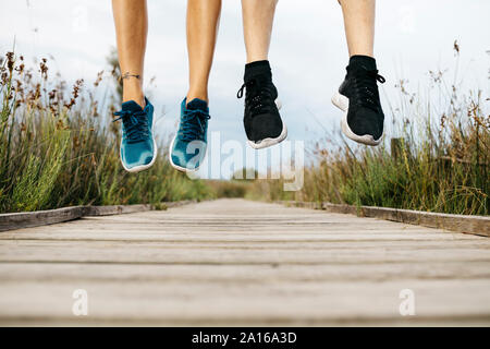 Feet of joggers jumping on a wooden walkway Stock Photo