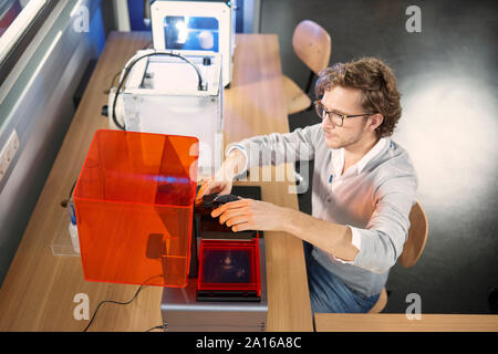 Technician sitting at table with 3D printer Stock Photo